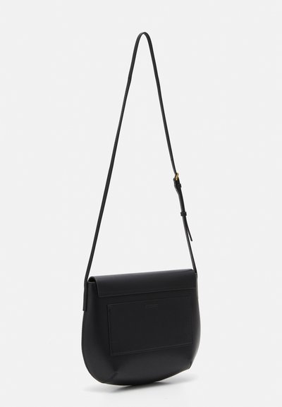 Sac en cuir noir à bandoulière avec une forme arrondie, poche frontale plate et sangle réglable ; texture lisse et design minimaliste.
