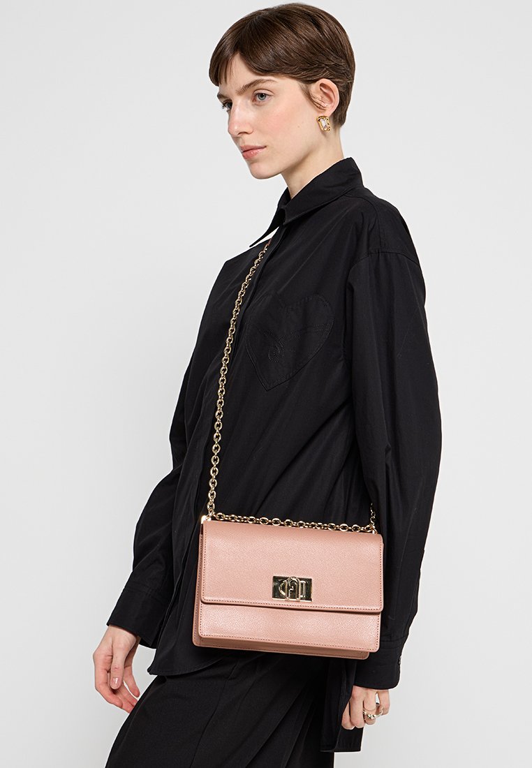 Rosa Lederhandtasche mit goldener Kettenriemen und metallischem Verschluss, rechteckige Form, glatte Textur und dezentes Maserungsmuster.