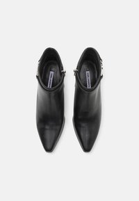Botine negre din piele, cu vârf ascuțit, textură netedă și un accent din metal argintiu la gleznă.