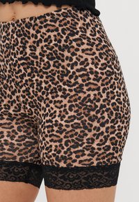 Shorts med leopardmønster som har en myk tekstur, en tettsittende design og svart blonderkant nederst.