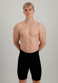  svarte, tettsittende shorts med en glatt tekstur, lett glans og ingen synlige sømmer, båret av en modell i en nøytral posisjon.