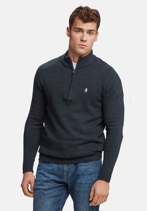 Dark grey knit sweater with a high collar and half-zip front. Features a small logo on the chest and ribbed cuffs and hem. Worn with blue jeans.