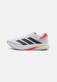 Baskets de sport blanches avec des rayures noires, des accents gris et une semelle vibrante rose et jaune. Tige texturée pour une meilleure respirabilité. Design à bout rond.