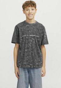 Halli mustriga t-särk lühikeste varrukatega, millel on ümmargune kaelus ja valged teksti detailid. Kombineeritud laia sinise teksapükstega.