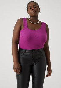 Fitted purple ribbed tank top with wide straps, paired with black glossy skinny pants. Chain necklace and textured skin visible.