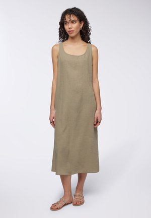Abito maxi senza maniche di colore verde salvia con scollatura quadrata, realizzato in tessuto testurizzato, che scende sotto il ginocchio; abbinato a sandali con cinturini.
