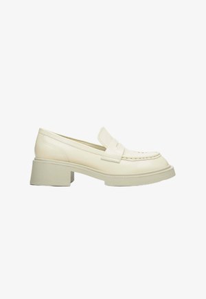 Cream-colored loafers with a low block heel, featuring a smooth leather finish, decorative stitching, and a rounded toe design.