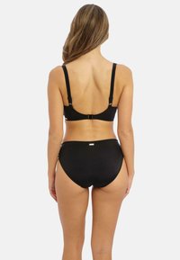 Ensemble bikini noir avec un design simple, des bretelles ajustables et une fermeture à clip à l'arrière. Texture lisse avec des accents matériels minimaux.