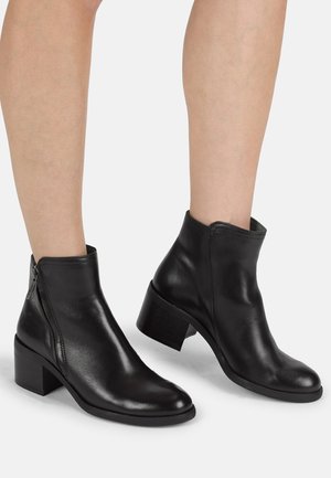 Black leather ankle boots with a rounded toe, side zipper, and a low block heel. Smooth texture with minimal hardware accents.
