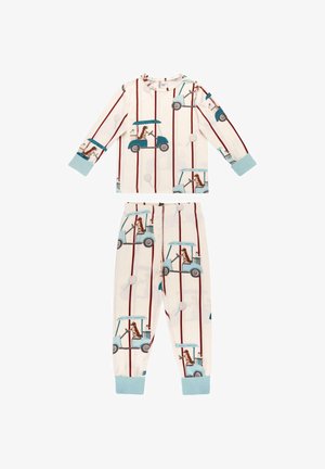 Bambino con capelli ricci in piedi scalzo su una sedia bianca con texture, indossando un pigiama con golf cart e cani marroni su uno sfondo bianco con strisce rosse.