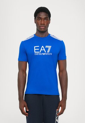 Niebieska koszulka z krótkim rękawem z logo "EA7 EMPORIO ARMANI" w kolorze białym. Pasiaste akcenty na ramionach, gładki materiał, dopasowany krój.
