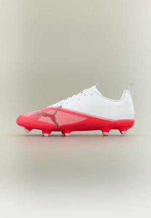 Biało-czerwony but piłkarski z sznurowadłami, logo Puma i podeszwą z korkami zaprojektowany do gry na twardym podłożu.