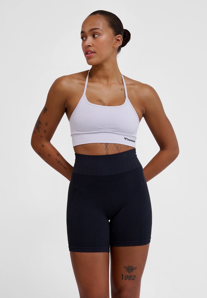 Lichtpaarse sportbh met een geribbelde structuur en verstelbare banden, gecombineerd met high-waisted donkerblauwe shorts met een gladde textuur.