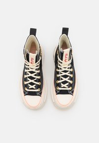 Sneaker alte con un rivestimento in denim scuro, lacci crema, dettagli rosa e occhielli dorati. Punta e suola in gomma bianca.