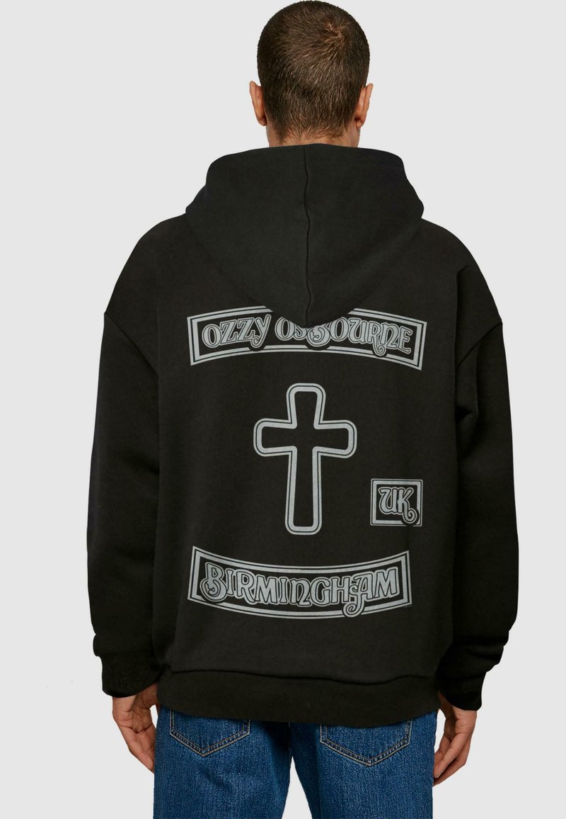 Sort hættetrøje med hvide grafikdetaljer: "OZZY OSBOURNE," et kors, "UK," og "BIRMINGHAM." Løs pasform og blød stofstruktur.