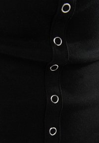 Svart ribbad tyg med silverfärgade ögla-knappdetaljer längs sidan. Slät textur och figurnära design.