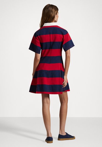 Gestreepte jurk met rode en marineblauwe horizontale strepen, korte mouwen, een kraag en een uitlopende rok. Casual stof met zichtbare stiksels.