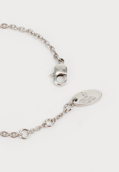 Silver chain bracelet featuring interlocking links, a lobster clasp, and an oval tag with embossed design. Smooth texture and polished finish.