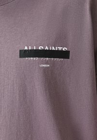 Sudadera de algodón morada con texto bordado en blanco y negro que dice 'ALLSAINTS' y 'LONDRES', además de una franja de acento negra.