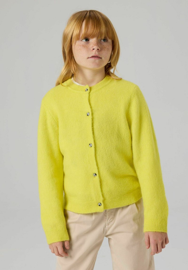 Gul ullcardigan med rund hals, knapper foran og ribbestrikkede mansjetter. Kortere lengde, myk tekstur og glatt finish.