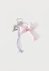 Μπρελόκ με γυαλιστερό ροζ φιόγκο, συνδεδεμένο με κορδόνια σε αποχρώσεις λεβάντας και ασημί, διακοσμημένο με λαμπερό γούρι σε σχήμα καρδιάς, όλα σε λευκό φόντο.