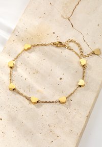 Bracciale a forma di cuore in oro con cuori solidi alternati a una delicata catena, dotato di una chiusura a galletto e lunghezza regolabile.