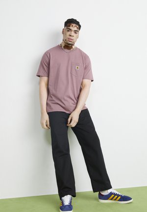 Light pink short-sleeve t-shirt with a chest pocket, paired with black pants, and blue shoes featuring yellow and red stripes.