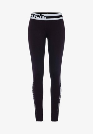 Black leggings with a wide white waistband featuring logo text. Side panels have a mesh geometric pattern. Fit is sleek and form-fitting.