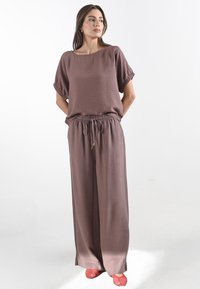 Twee-delige outfit met een losse top met korte mouwen en een broek met brede pijpen in mauve kleur, gemaakt van een gestructureerde stof met een elastische tailleband.