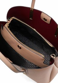 Beige leren tote bag met gouden hardware, voorzien van een rode binnenkant, ritssluitingen en een gestructureerde zwarte voering.