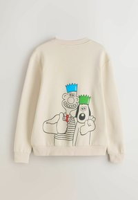 Beiger Pullover mit einer Grafik von zwei Figuren mit blauen und grünen Kronen, schwarz umrandet, die ein gestreiftes Hemd tragen und mit dem Daumen nach oben zeigen.