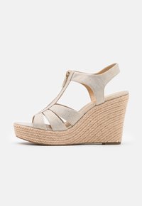 Sandalia de cuña beige con parte superior de tela texturizada y tiras entrelazadas, que cuenta con una cremallera en el lateral y una base similar a una cuerda trenzada.