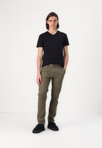 Černé tričko s výstřihem do V, olivově zelené slim-fit kalhoty a černé boty. Hladká tkanina, přiléhavý střih a základní jednobarevné barvy bez vzorů.