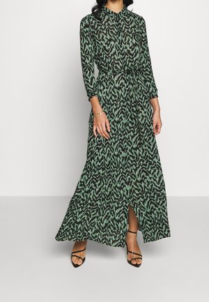Robe longue verte avec un motif abstrait noir, col et manches trois-quarts. Comprend une fente à l'avant et une taille nouée. Paire de talons aiguilles noirs à lanières.