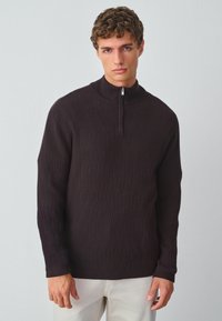 Donkerbruine gebreide pullover met een halve rits kraag, voorzien van een gestructureerd ruitpatroon en lange mouwen. Zachte stof en een relaxte pasvorm.