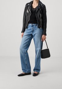 Black leather biker jacket, black lace top, light blue high-waisted jeans, black flat shoes, and a small black textured handbag.