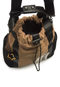 Braune und schwarze Stoff-Bucket-Tasche mit Kordelzugverschluss, Nylonriemen und gelben Akzenten. Verfügt über eine Seitenöffnung und Logo-Detail.
