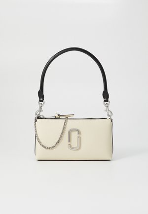 Bolso color crema con un asa negra, detalle de cadena plateada y un logotipo destacado en el frente. Textura suave y cierre con cremallera.