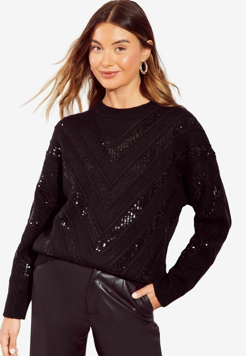 Maglione nero a maglia con motivo a zigzag e dettagli in paillettes, caratterizzato da un collo rotondo e maniche lunghe, abbinato a pantaloni neri.