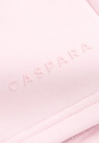 Rosa tekstil med en jevn tekstur har det pregete ordet "CASPARA" i en lys nyanse, satt mot en subtil bakgrunn.