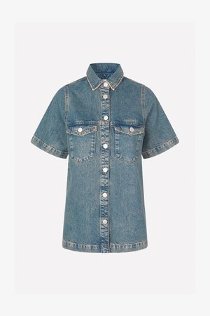 Denimskjorte i lys blå med korte ermer, knappestolpe foran, to brystlommer og kontrastsøm. Klassisk kragedesign.