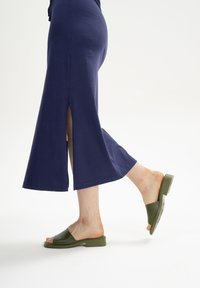 Marineblaues Midikleid mit seitlichen Schlitzen, aus Baumwolle gefertigt. Kombiniert mit olivgrünen Riemensandalen mit Blockabsatz und offenem Zehendesign.