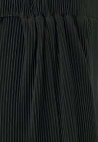 Tissu noir plissé avec des lignes verticales, présentant une surface texturée, froncé à la taille avec un léger éclat et une tombée douce.