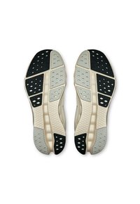 Semelles de chaussures en beige, gris et noir avec un motif en nid d'abeille. Surface texturée et perforations pour une traction optimale. Design symétrique.