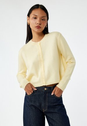 Cárdigan de punto amarillo con escote redondeado, cerrado por botones en la parte delantera, con mangas largas y un diseño corto.
