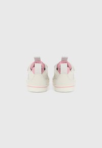 Lys grå semsket sneakers med rosa aksenter, har en ekstrastropp på hælen, og en hvit såle med en rosa stripe. Mykt, teksturert materiale.