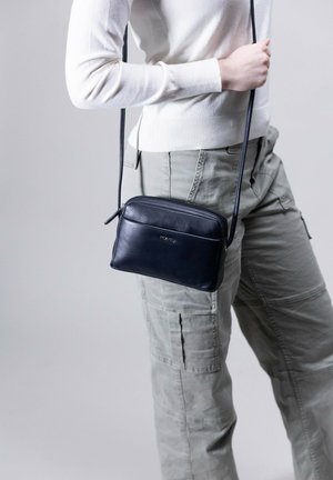Navy Leder Umhängetasche mit Reißverschluss, glatter Textur und schlankem rechteckigem Design, das ein leichtes Logo-Detail auf der Vorderseite aufweist.