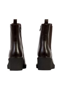 Paire de bottines en cuir marron foncé avec fermetures éclair latérales et talons noirs épais, vues de dos.