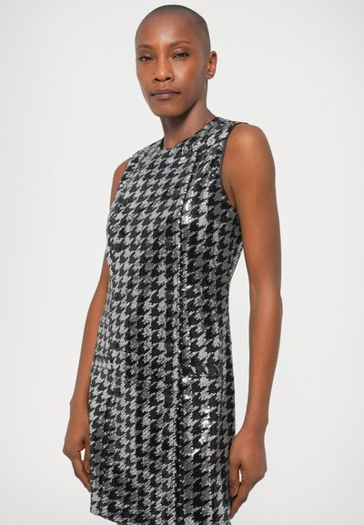Μαύρο και ασημί φόρεμα χωρίς μανίκια σε σχέδιο houndstooth, με υφή από πούλιες, εφαρμοστή γραμμή και διακριτικές πλευρικές τσέπες.