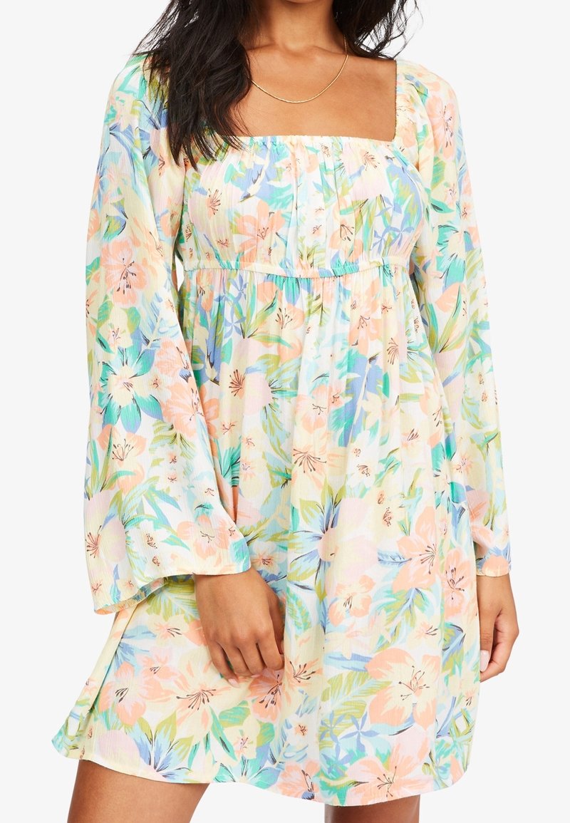 Robe fleurie avec un décolleté carré, des manches longues évasées et une taille élastique. Présente des couleurs pastel, de grands motifs floraux et un tissu léger.